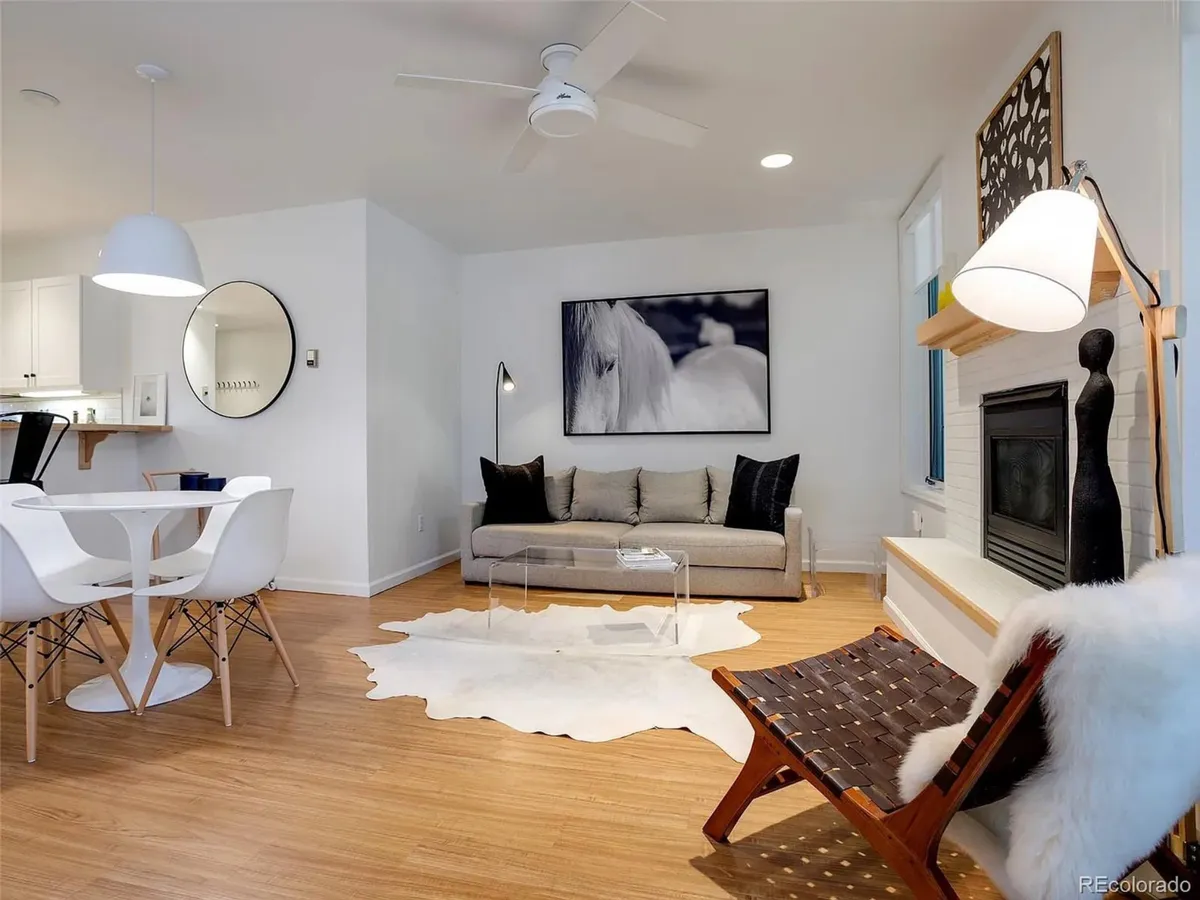 The image showcases a stylish and comfortable open-concept living and dining area within the condo. The cozy sofa and accent chair are arranged around a modern fireplace, inviting guests to relax after a day on the slopes. Artwork adds a touch of contemporary flair, while the dining table offers a perfect spot for shared meals or game nights.