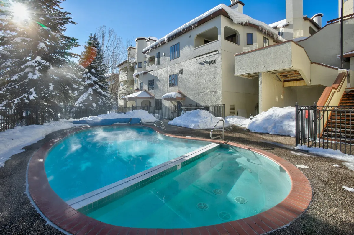 A striking visual of a swimming pool surrounded by snow, with the building’s architecture in the backdrop. This juxtaposition highlights the unique amenity of relaxing in a heated pool or hot tub after a day on the slopes.